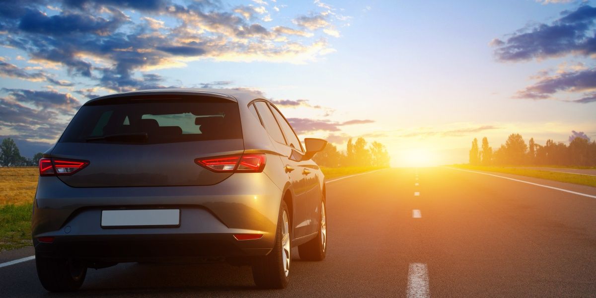 voiture de dos sur la route face au coucher de soleil