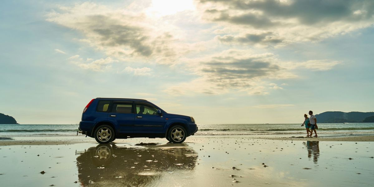 voiture sur la plage avec la mer et un ciel nuageux en fond