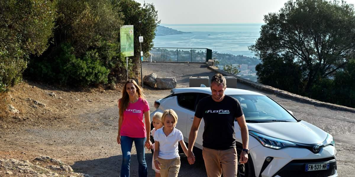 Family walking on hill next to car